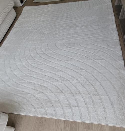 A white rug is sitting on a wooden floor in a living room.