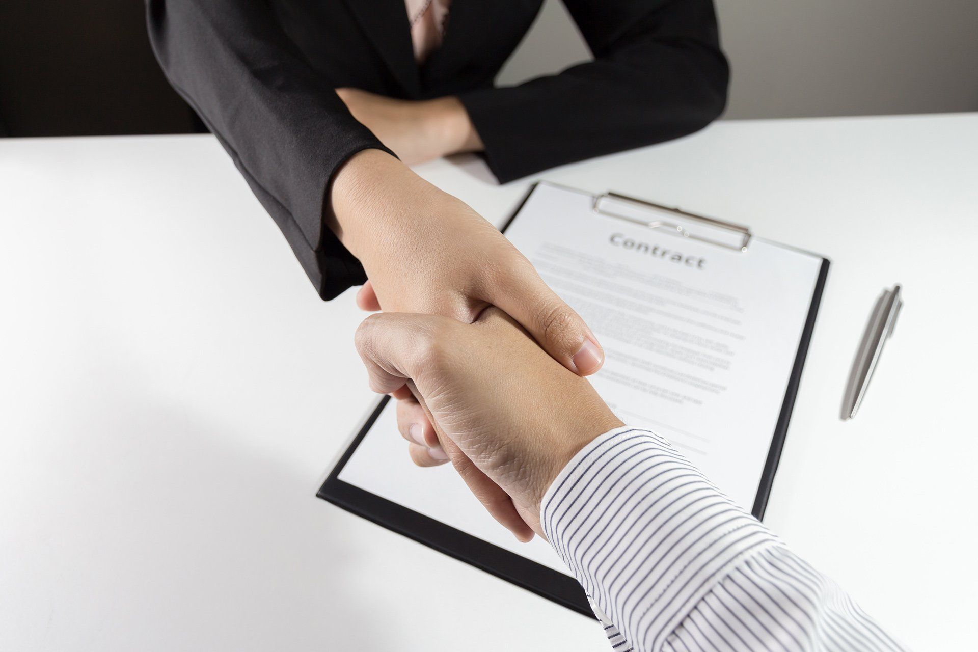 A man and a woman shaking hands over a contract