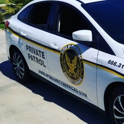 White security patrol car with black and gold branding.