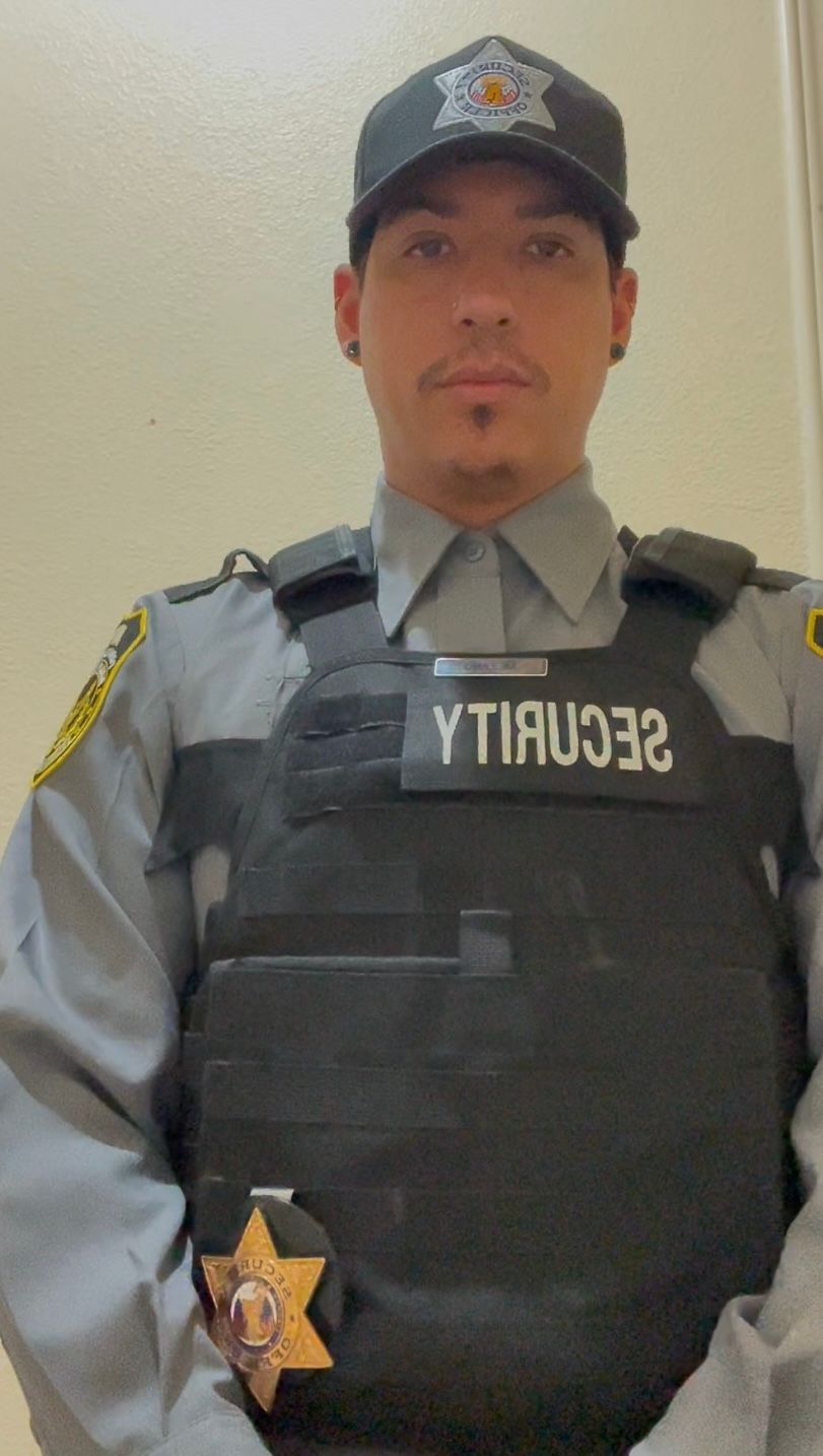 A man in a police uniform is standing in front of a white wall.