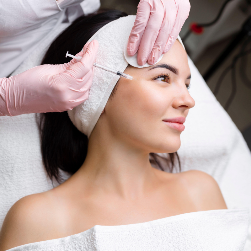 Cosmetic injection being administered to a woman’s forehead in a spa treatment room