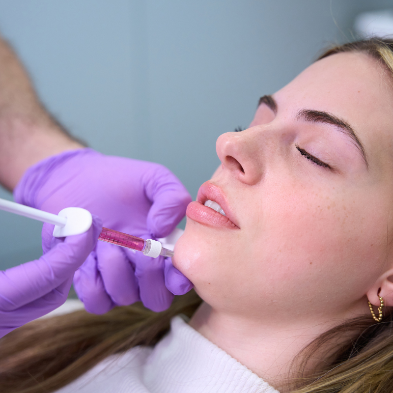 Cosmetic lip injection being administered to a relaxed client by gloved clinician