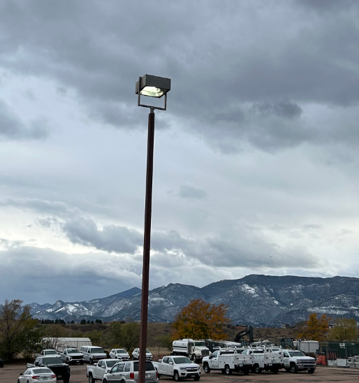 A lot of cars are parked in a parking lot with mountains in the background