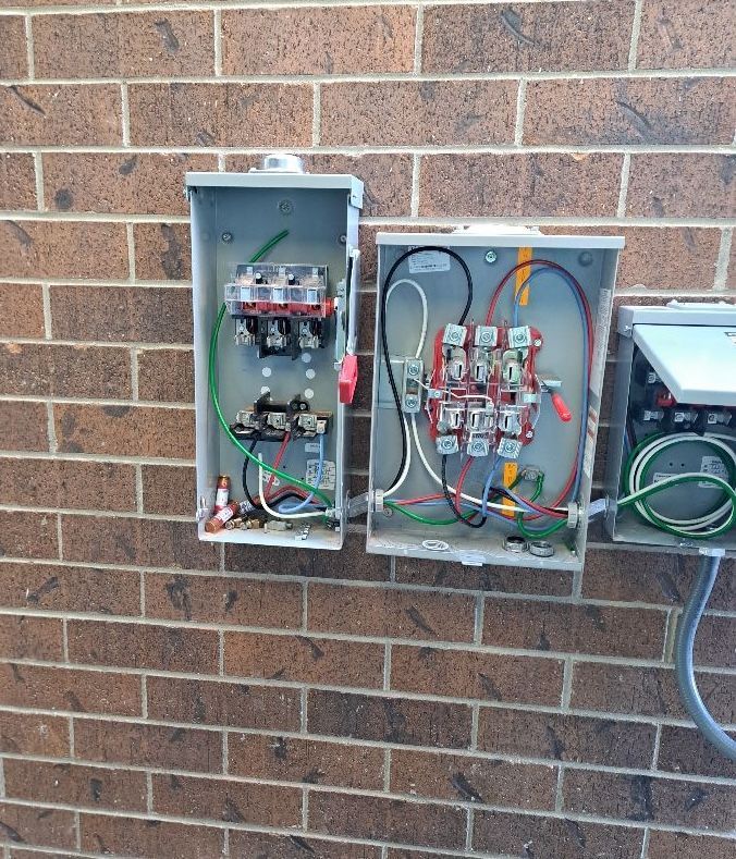Two electrical boxes on a brick wall with wires coming out of them