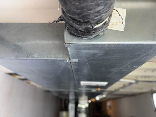 Metal ductwork attached to ceiling, with flexible ducting and connecting hardware visible.