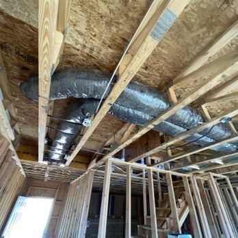 Wooden framing of a house under construction, with exposed HVAC ductwork running along the ceiling.