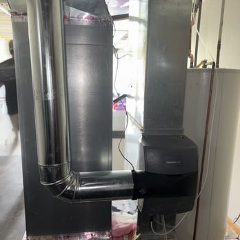 Furnace with metal ductwork, water heater to the right. A person is partially visible in the background.