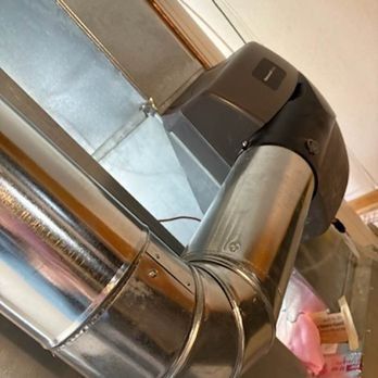 Metal ductwork with a humidifier attached, against a wall.