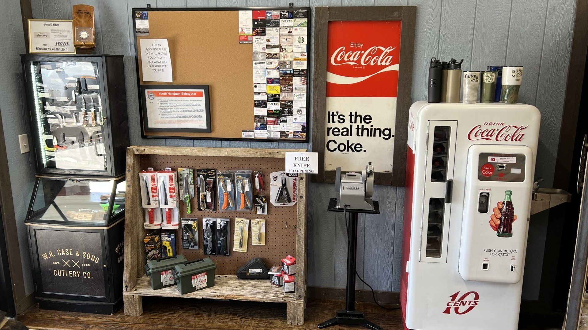 A coca cola vending machine is in a room with other vending machines