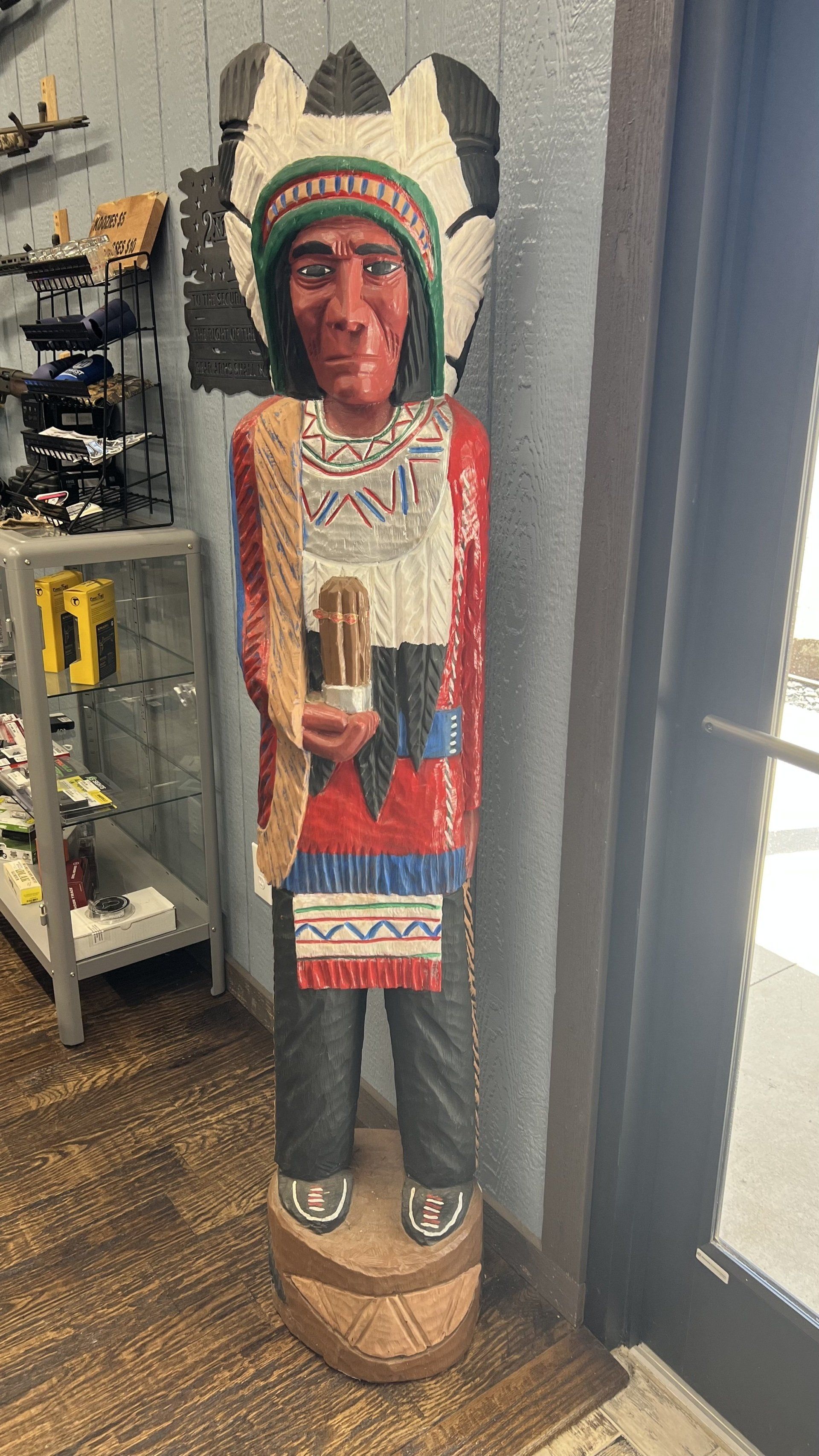 A statue of a native american chief holding a cup in a room.