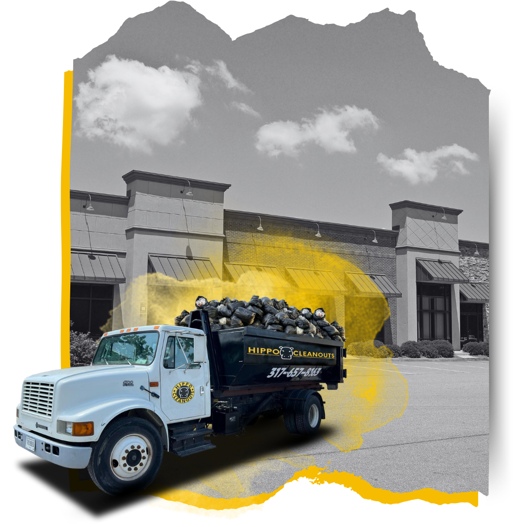 A Hippo Cleanout dumpster truck loaded with garbage in front of a commercial building.