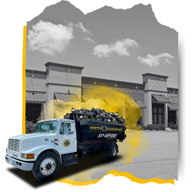 A Hippo Cleanout dumpster truck loaded with garbage in front of a commercial building.