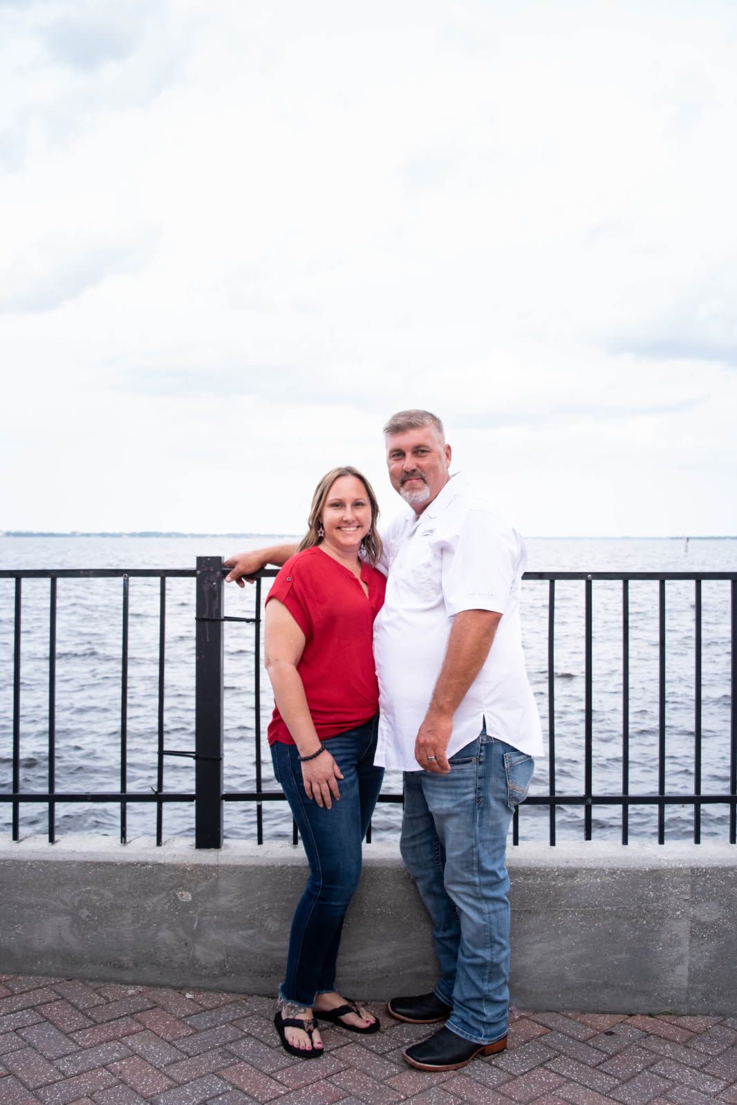 A man and a woman are standing next to each other in front of a fence.