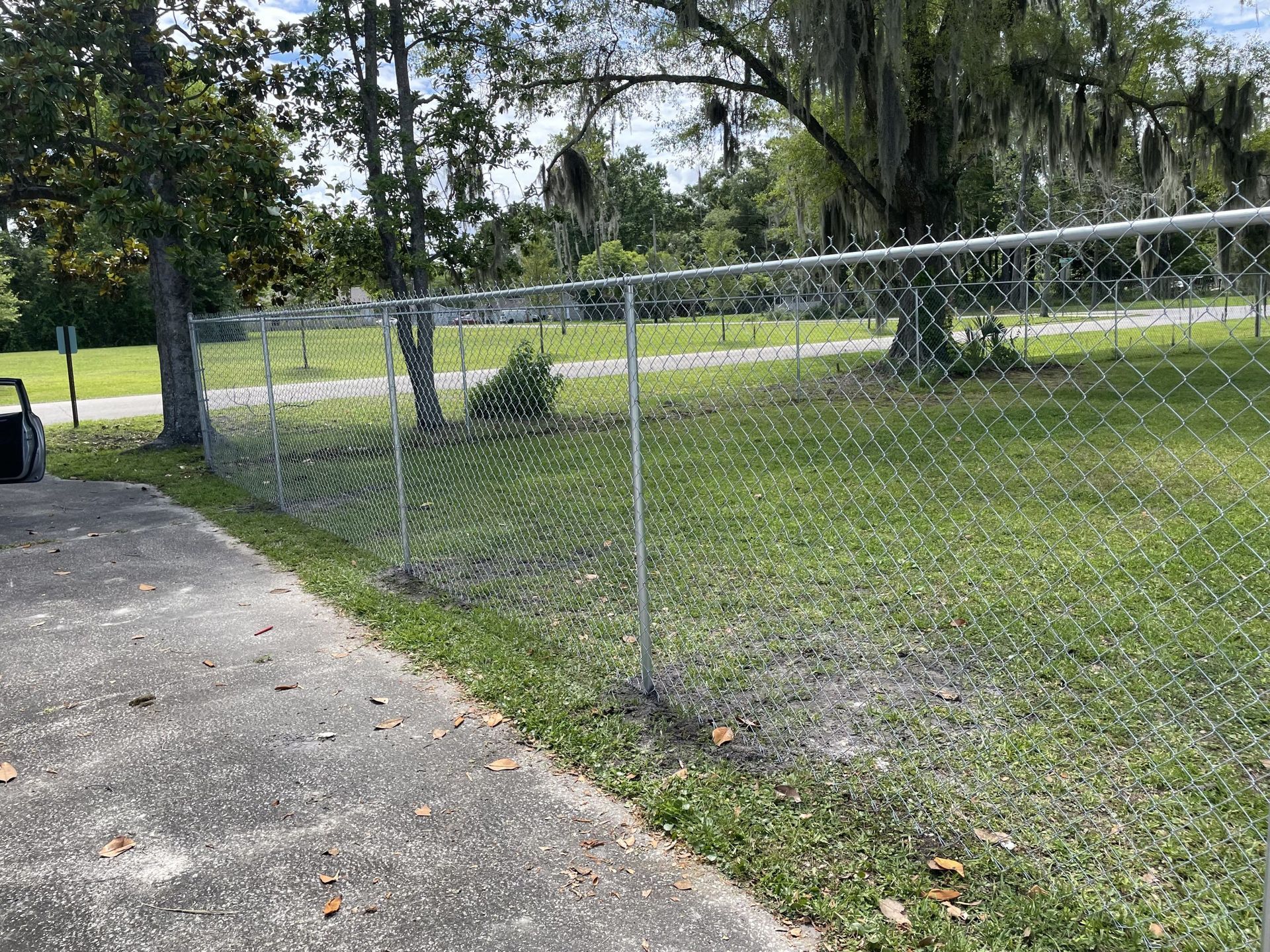 A chain link fence surrounds a lush green field.