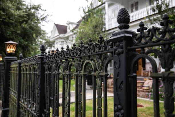 A black wrought iron fence is in front of a white house.