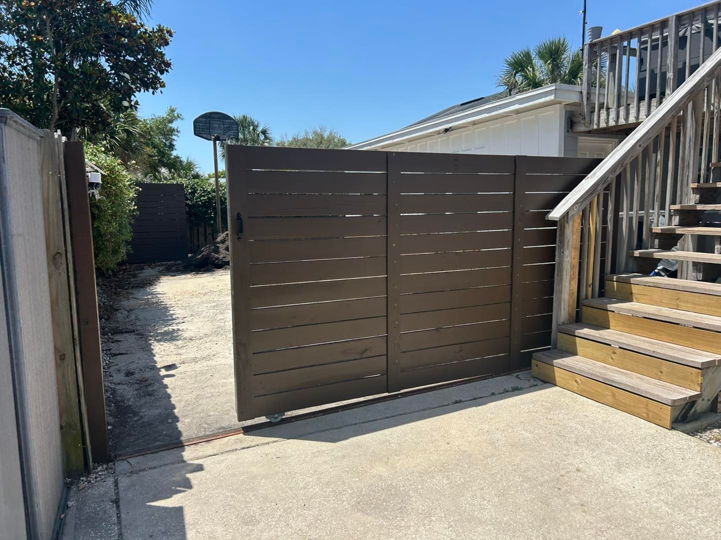 A fence with a house in the background and a cloudy sky.