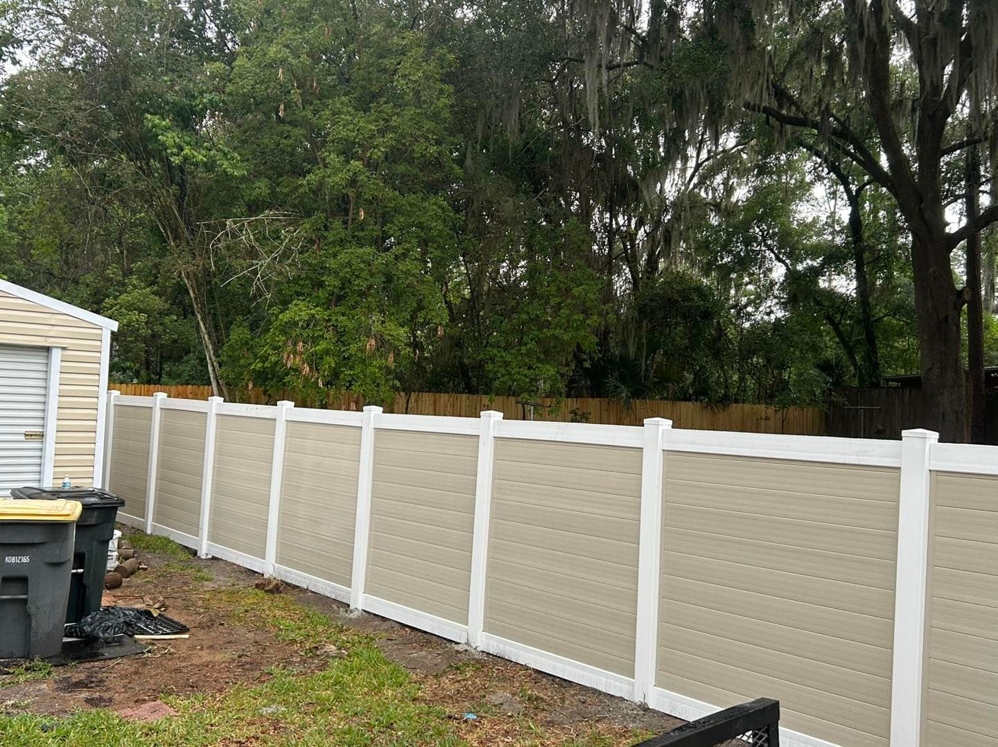 A person is using a drill to install a metal fence.