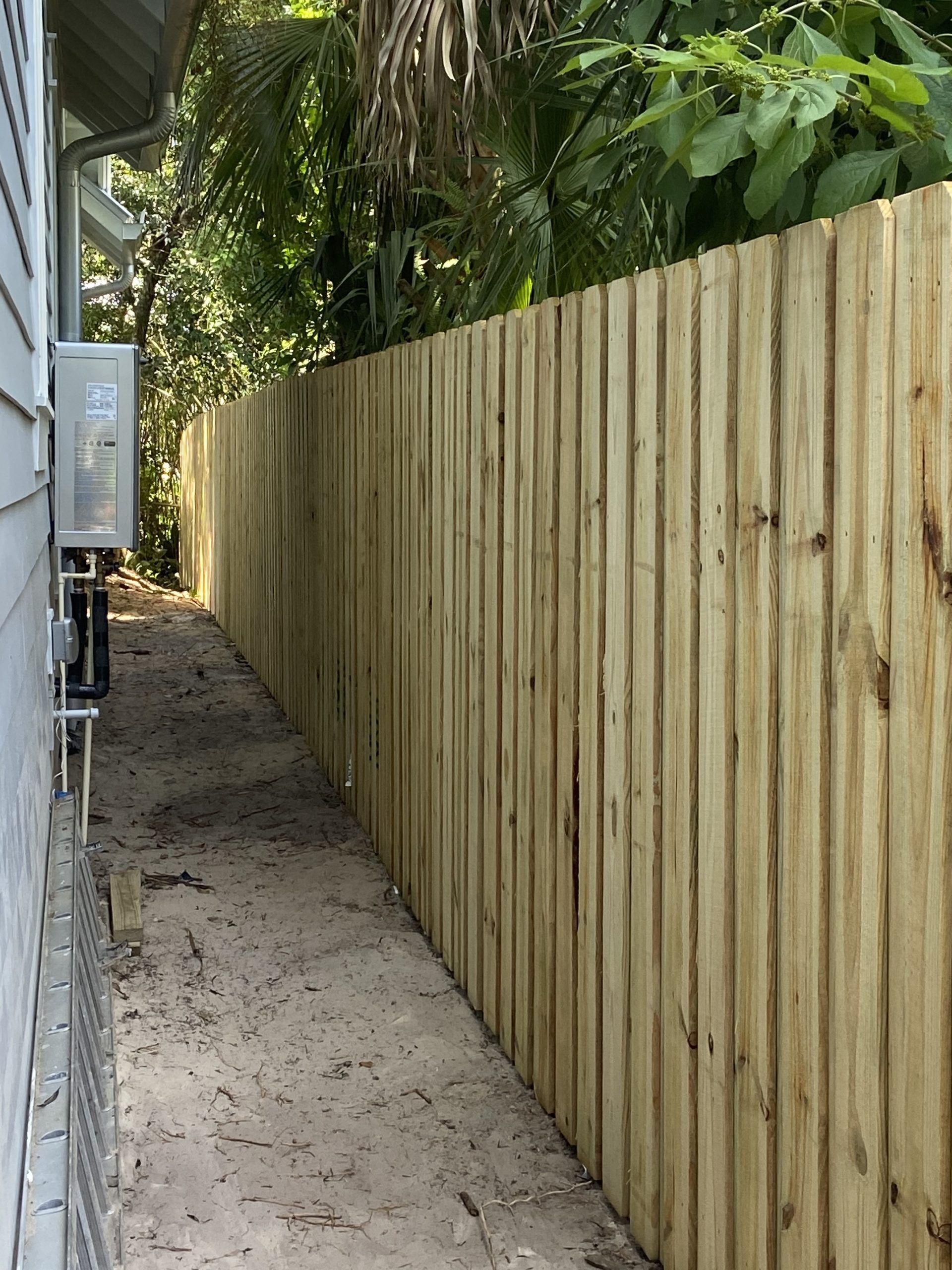 A wooden fence is along the side of a house.