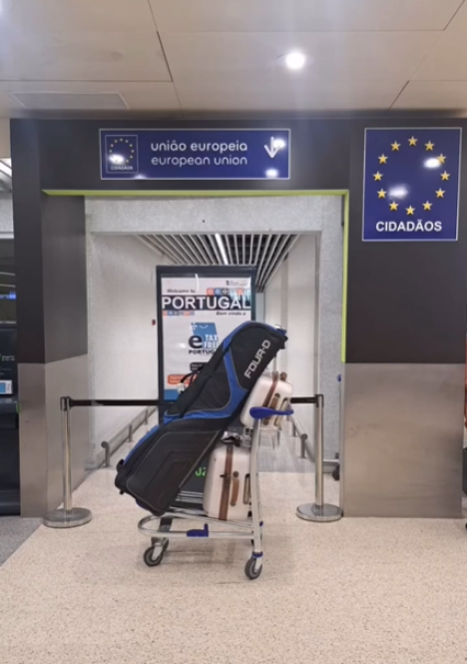 Umbrella stroller at an airport entrance beneath EU and Portugal signs