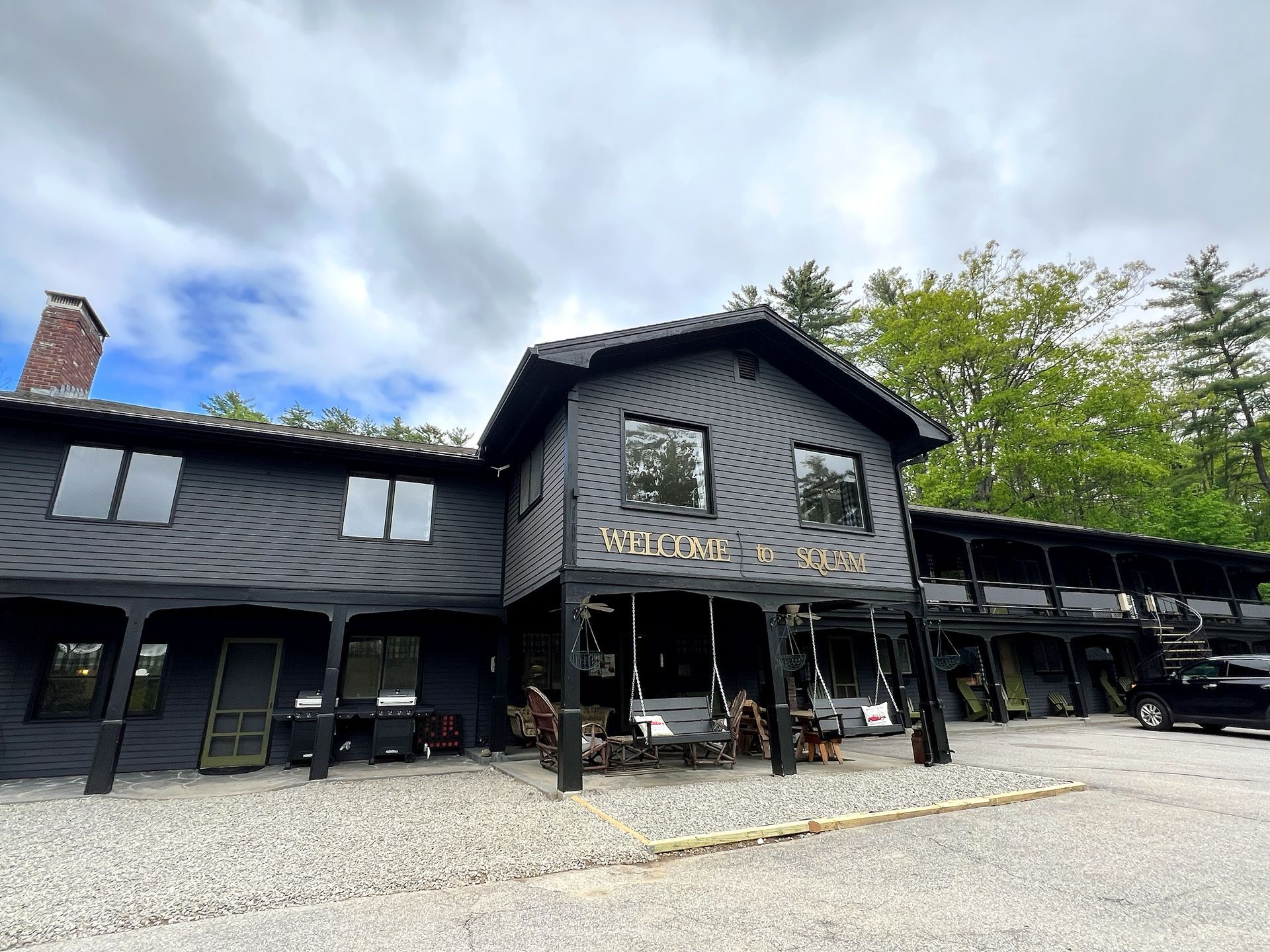 A large black house with a lot of windows is surrounded by trees.