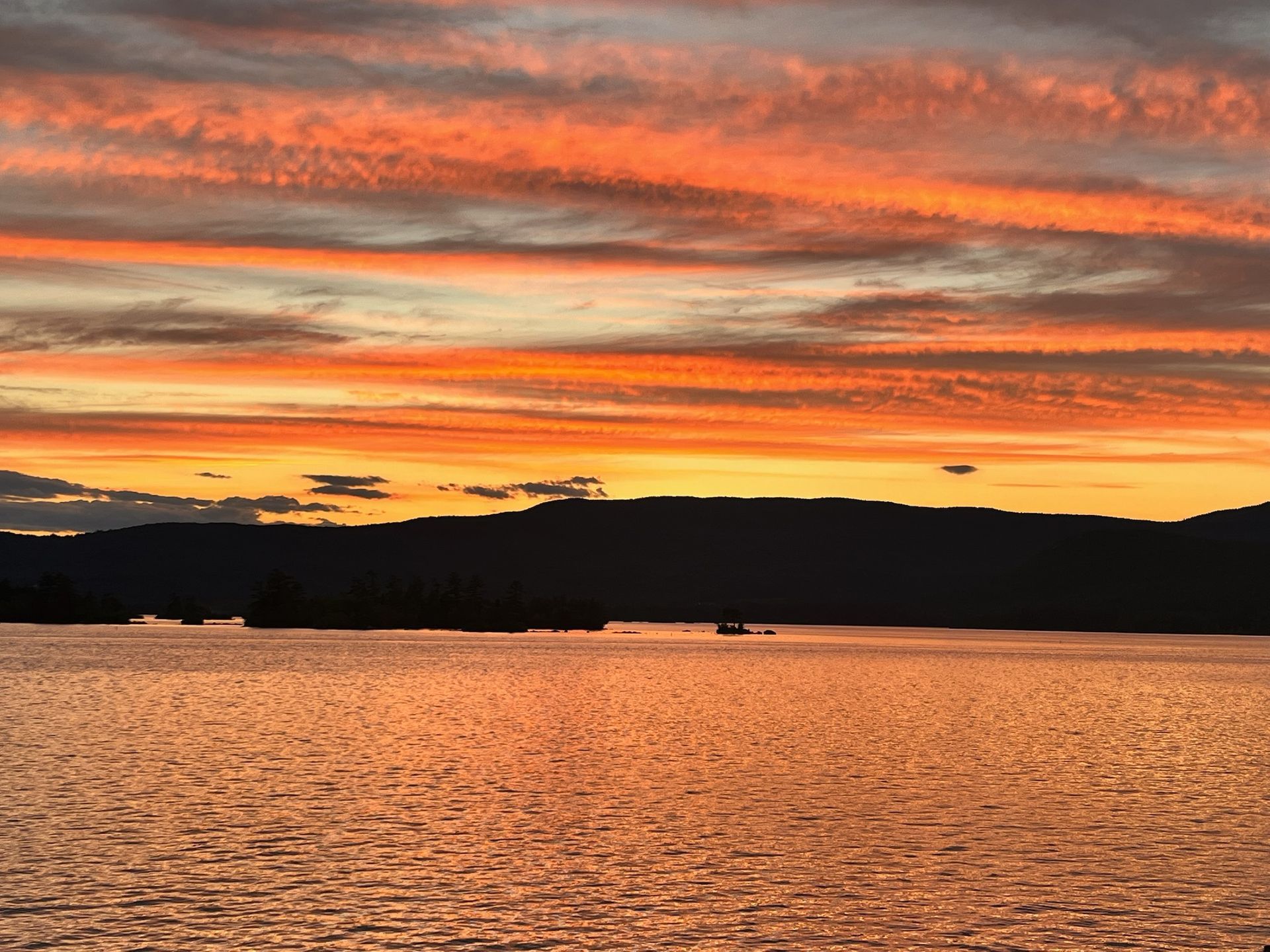A sunset over a body of water with mountains in the background