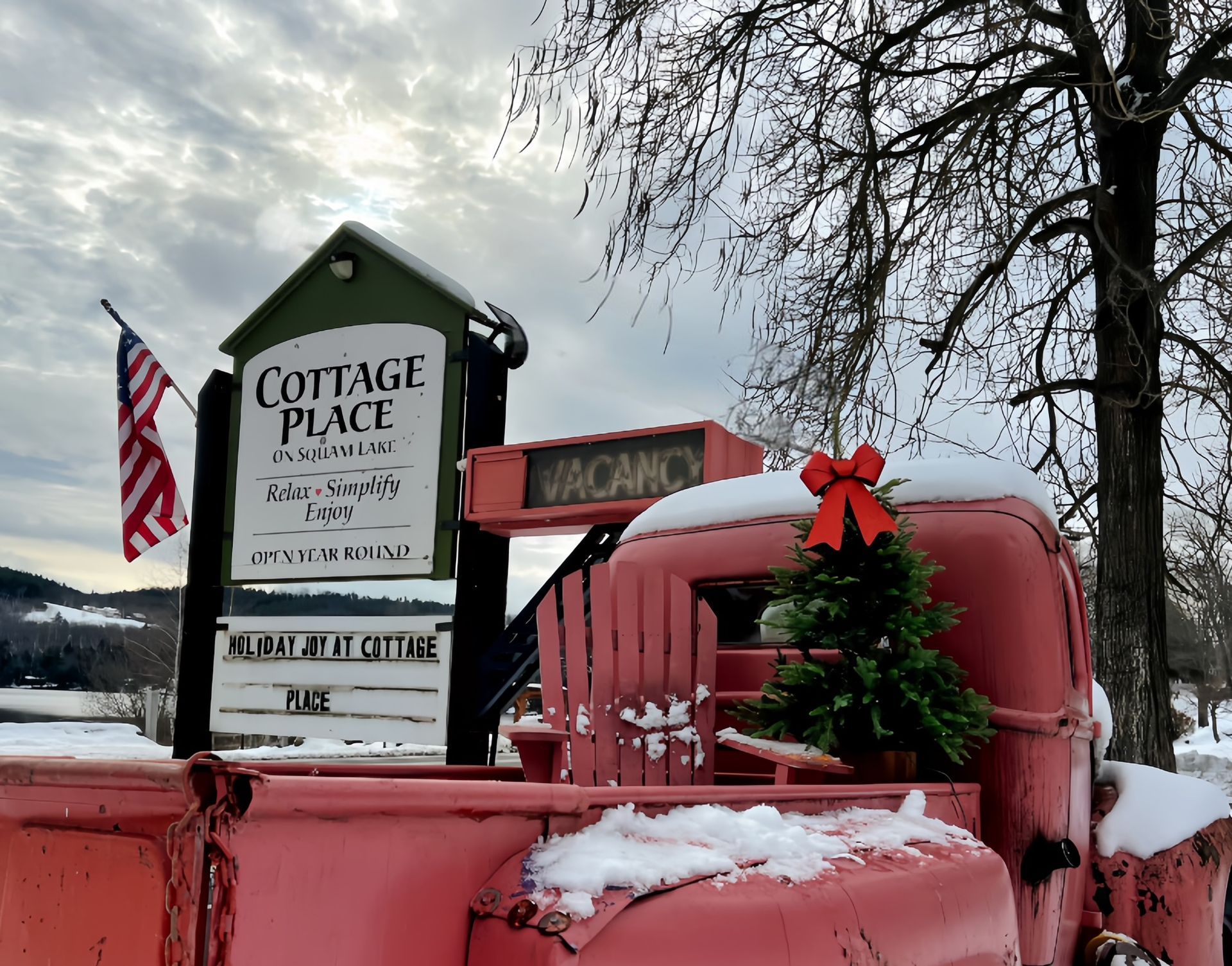 A red truck is parked in front of a sign that says cottage place