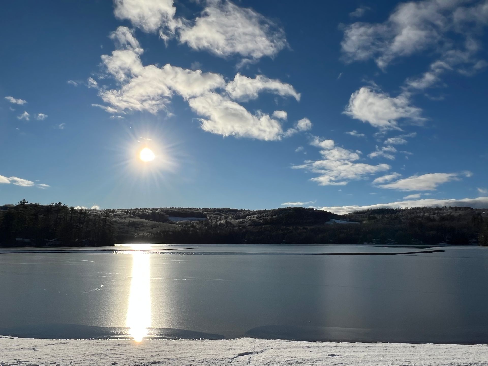 The sun is shining through the clouds over a lake