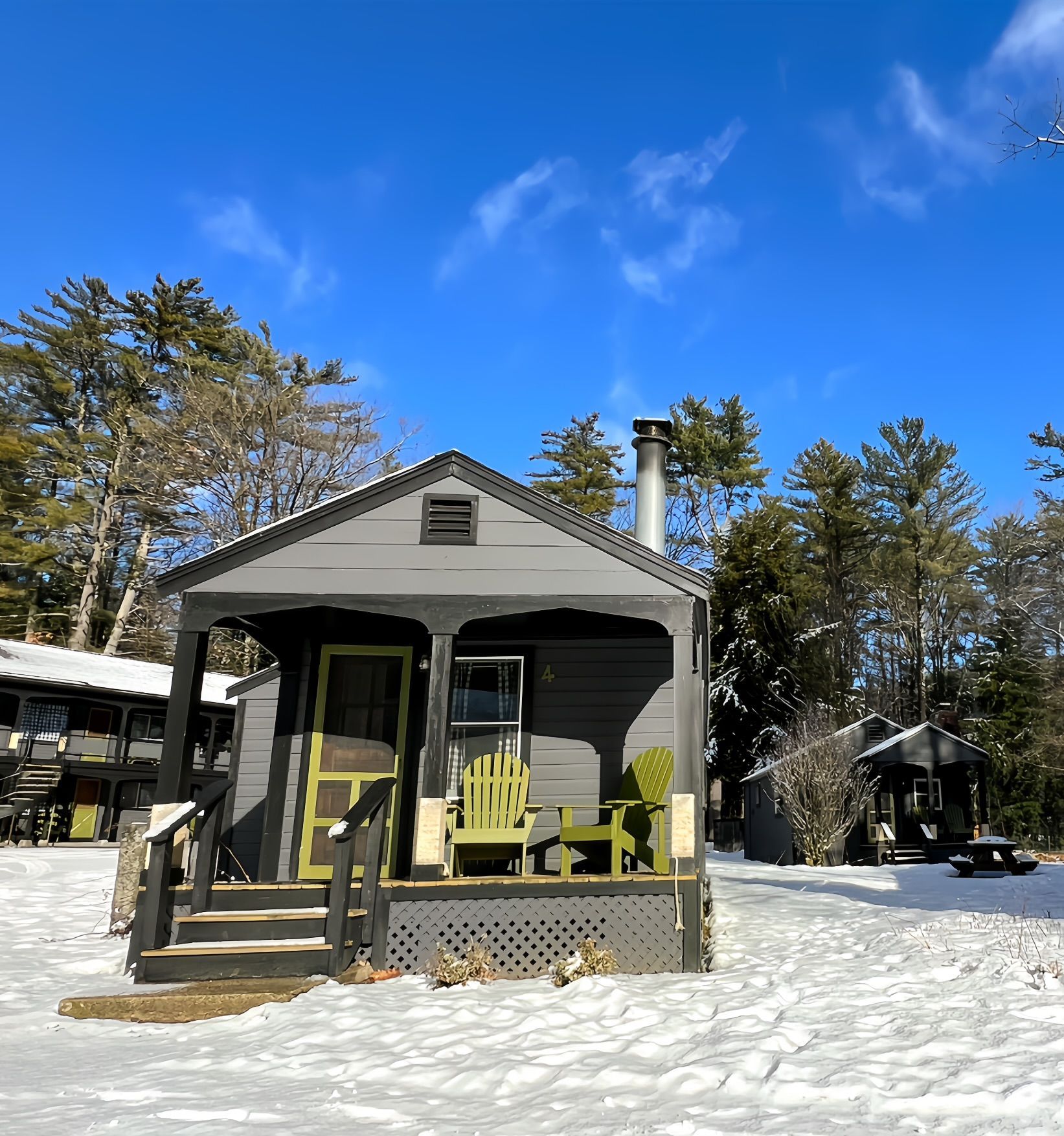 A small house with a porch and chairs in the snow