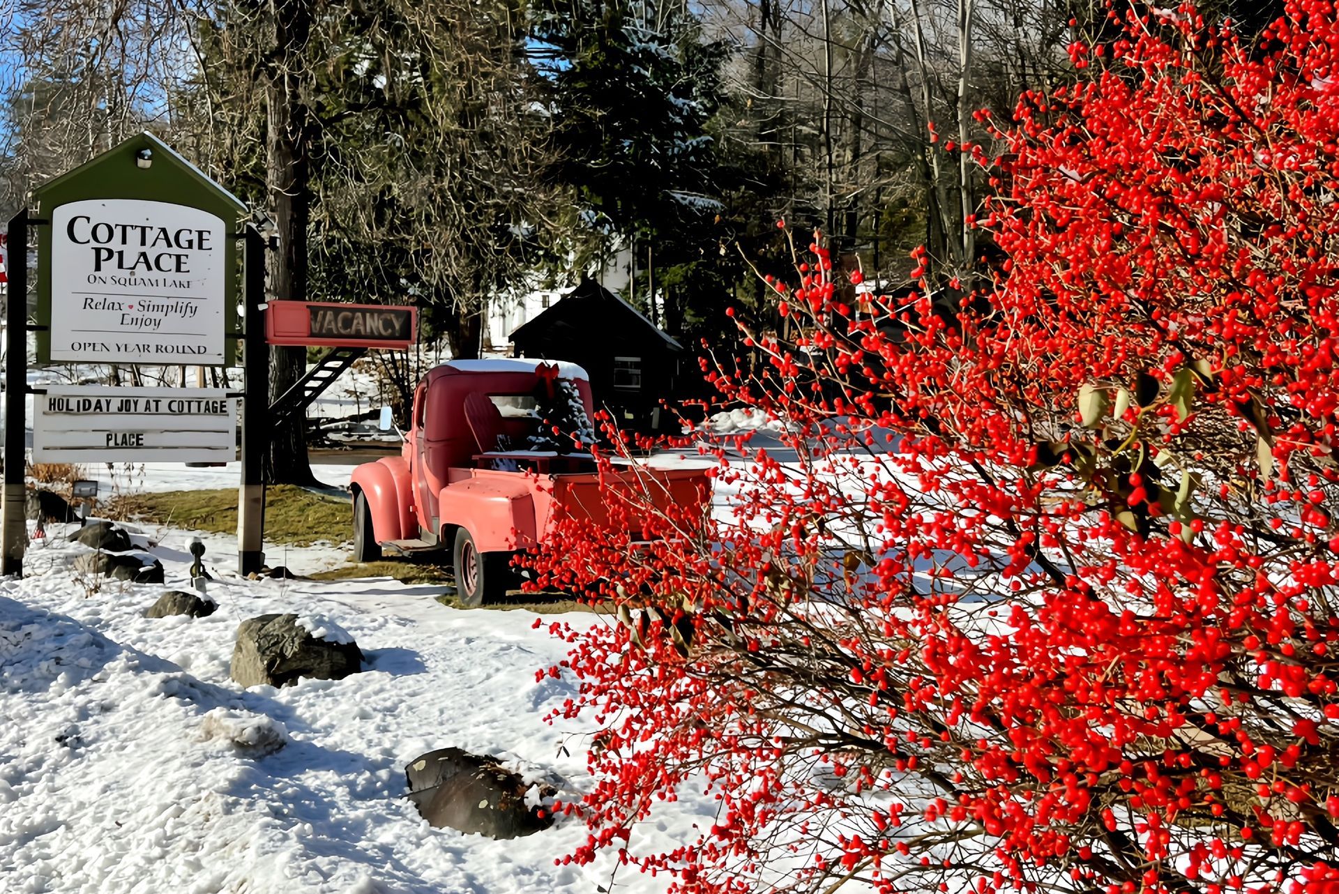 A red truck is parked in front of a sign that says cottage place