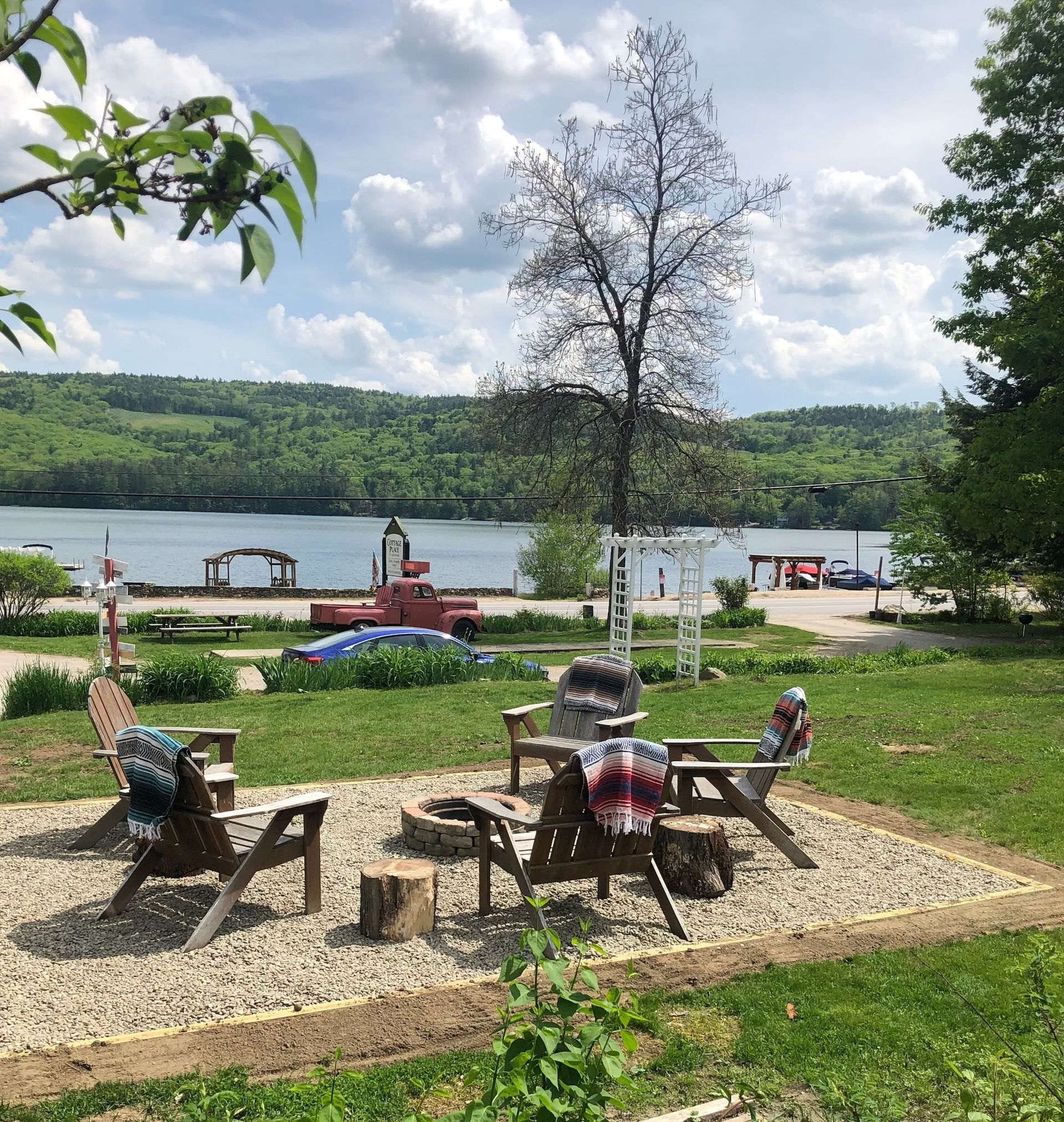 A group of chairs are sitting in a grassy area near a lake.