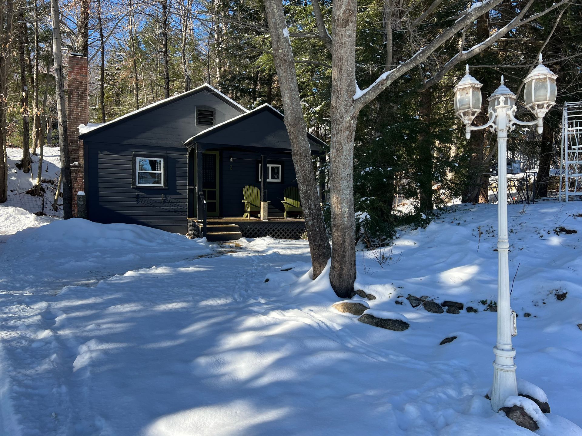 A small house is surrounded by snow and trees.