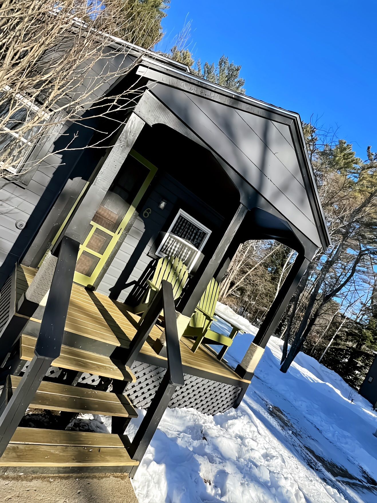 A small house with a porch and stairs in the snow.