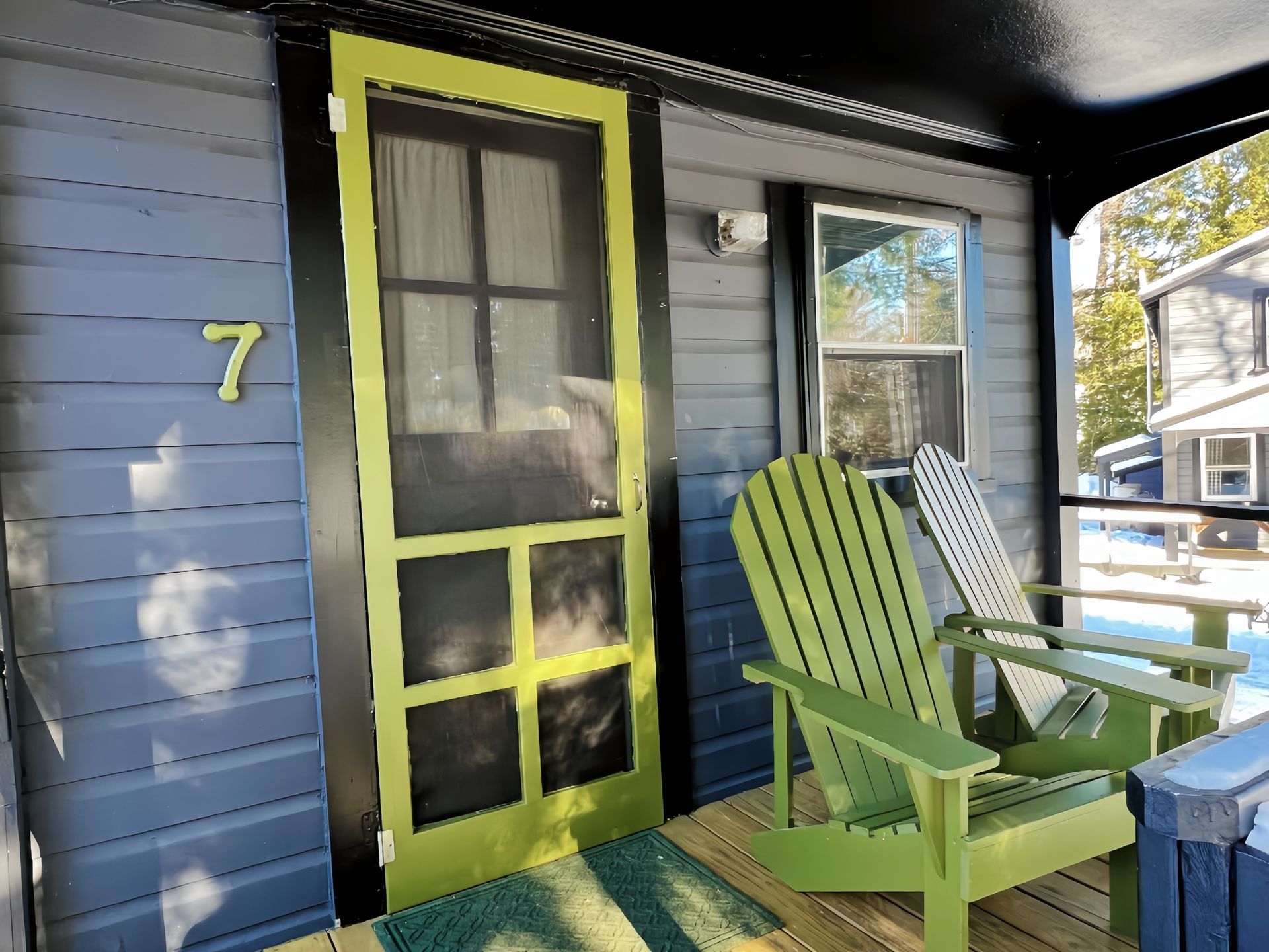 A porch with two green chairs and the number 7 on the door