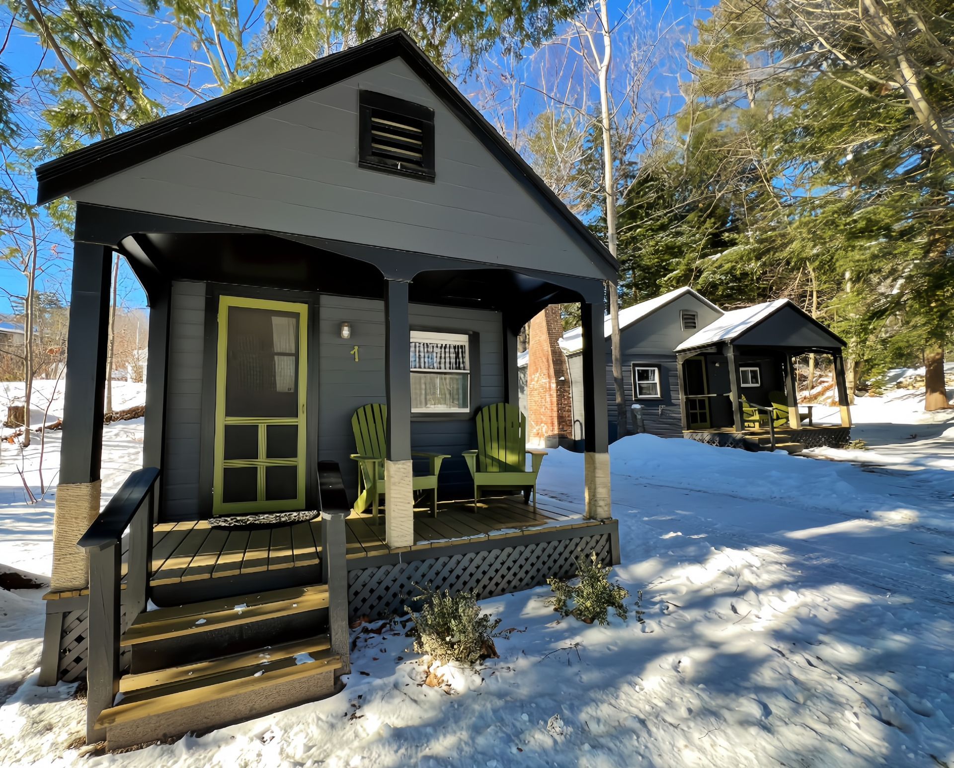 A small house with a porch and chairs in the snow