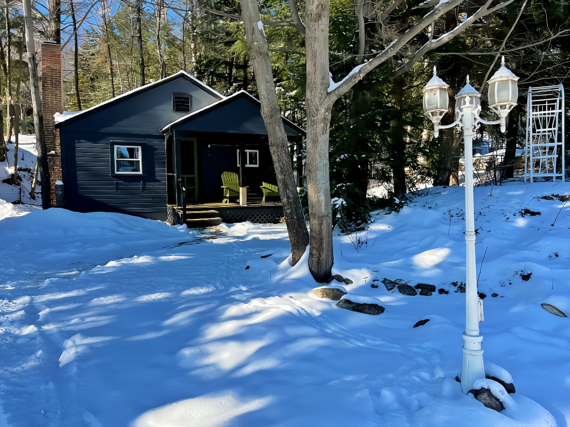 A black house is surrounded by snow and trees