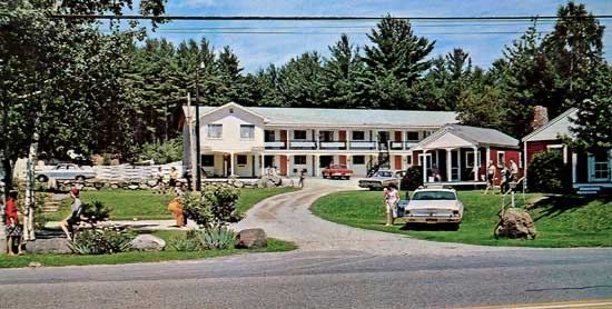 A motel with a lot of cars parked in front of it