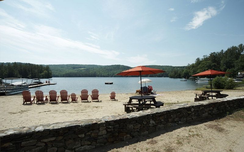 A beach with chairs and umbrellas and a lake in the background