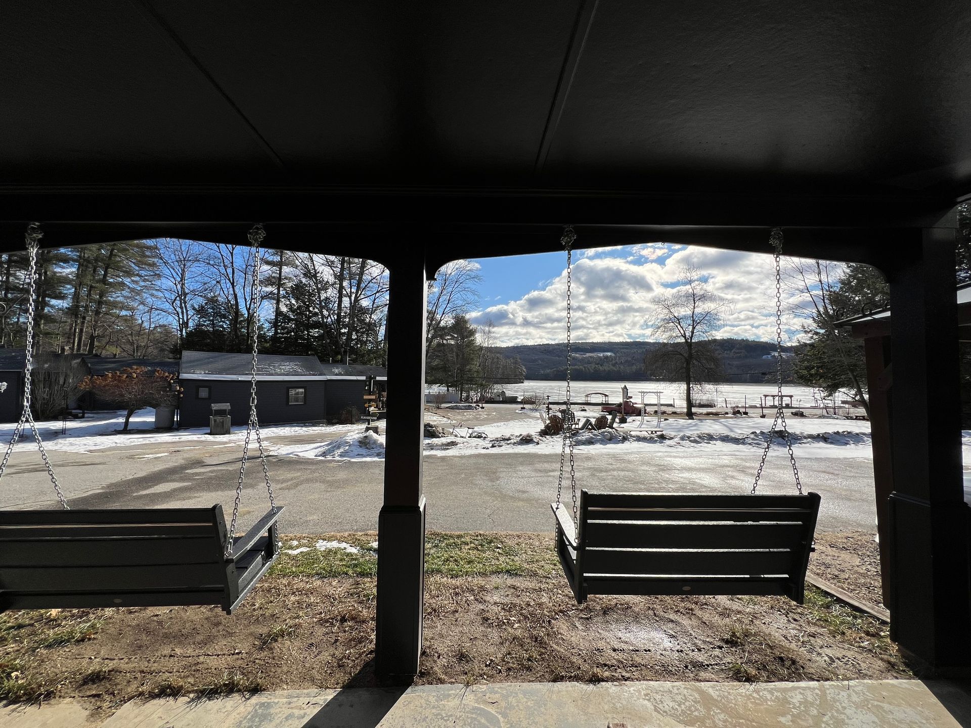 A porch with two swings and a view of a snowy field