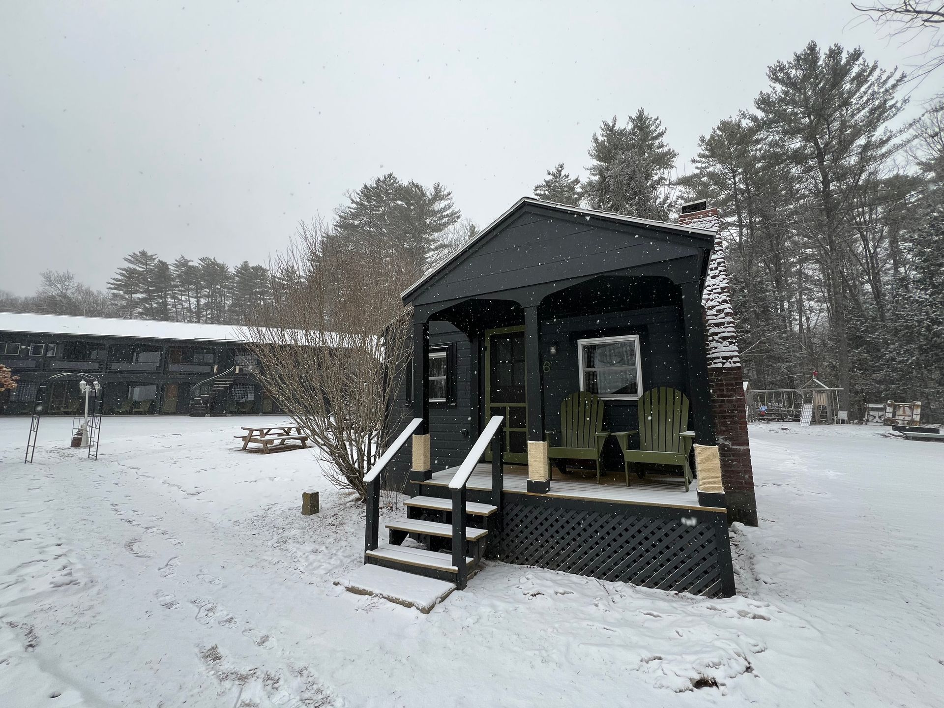 A small black house with a porch is covered in snow.