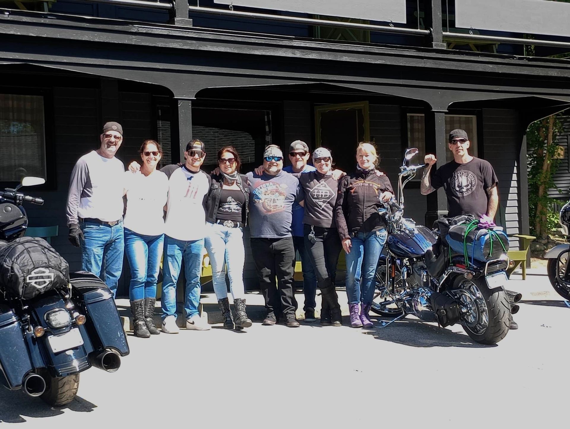 A group of people posing for a picture with motorcycles in front of a building