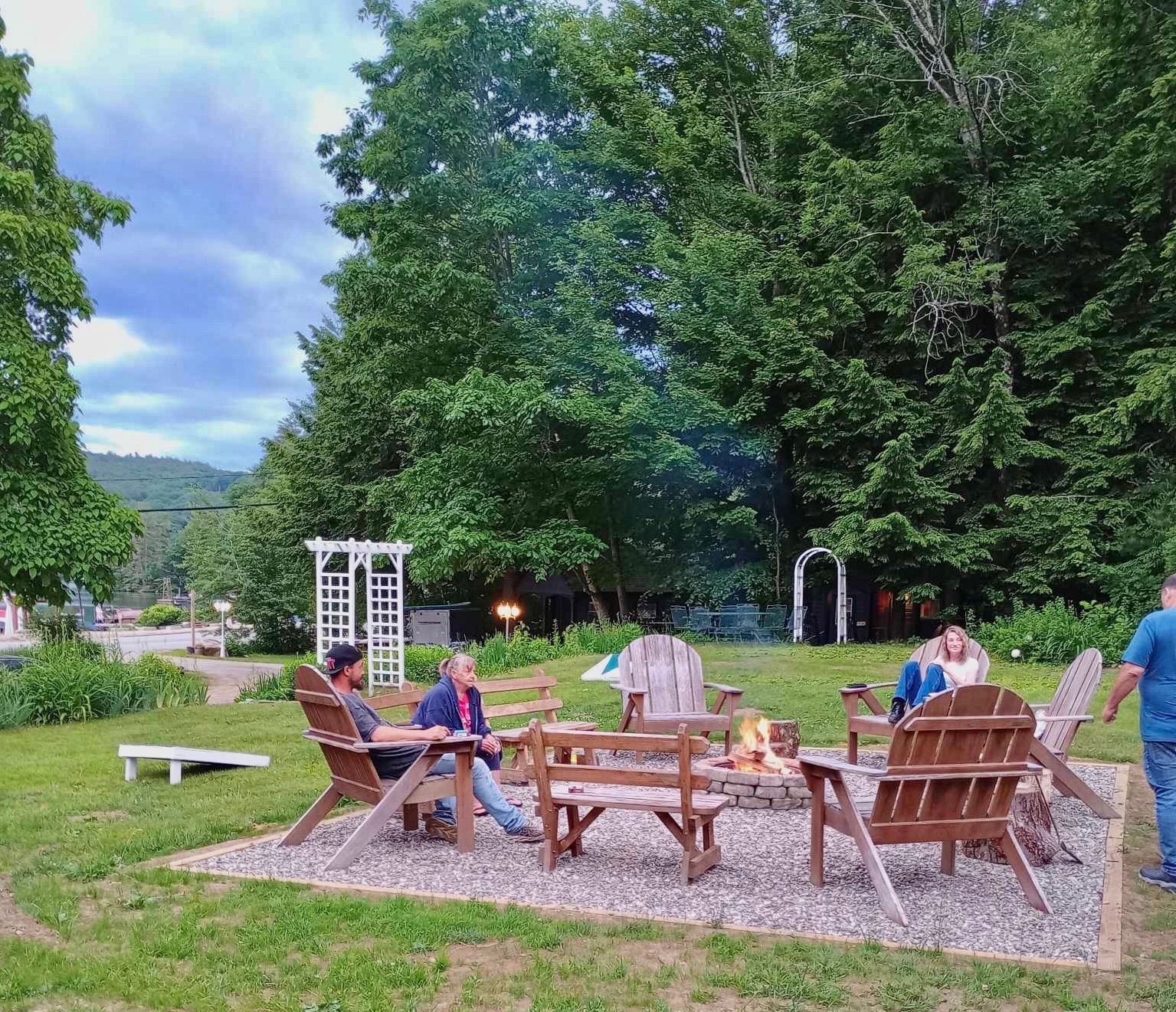 A group of people are sitting around a fire pit in a park.