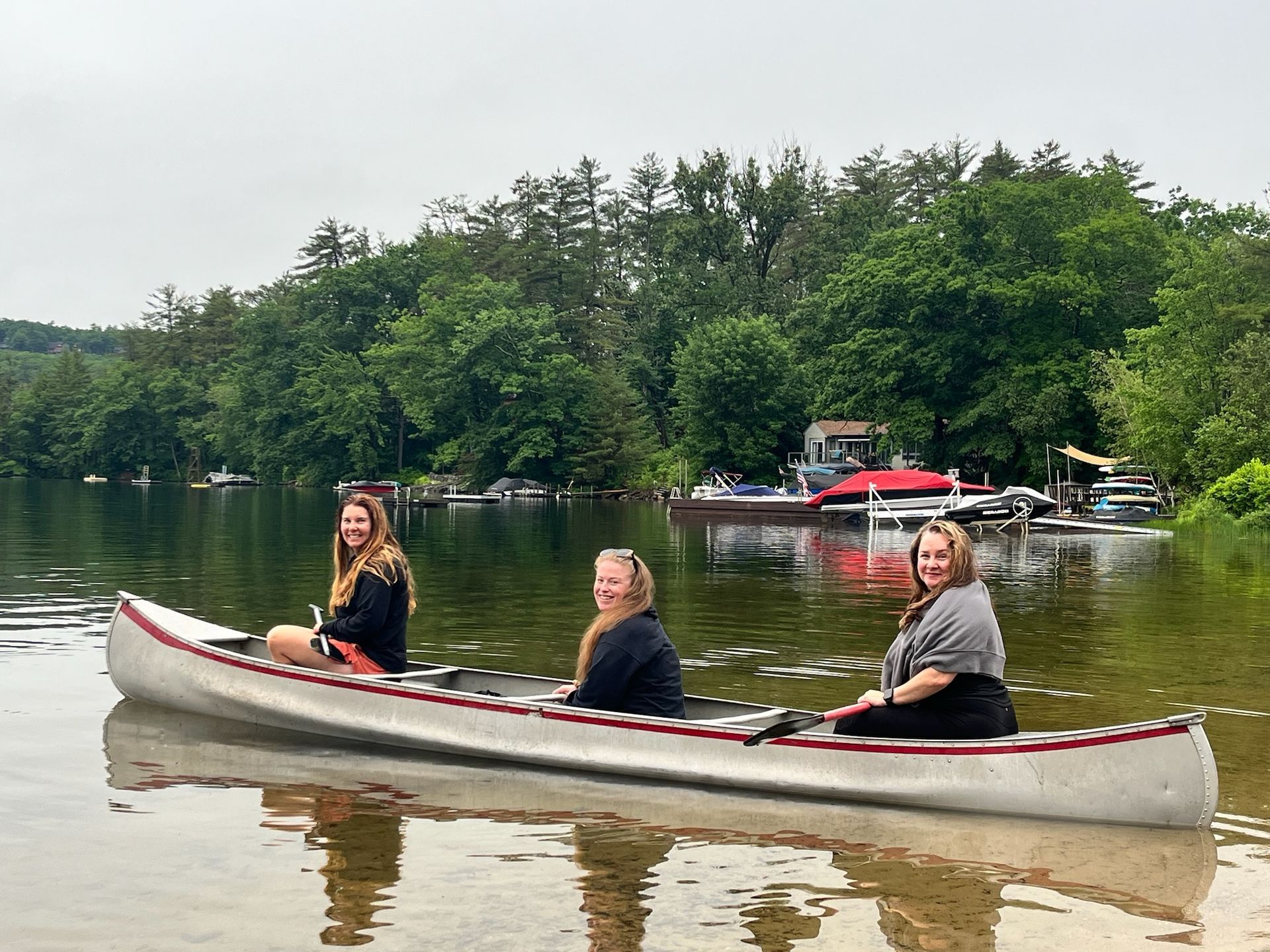 Three women are sitting in a canoe on a lake.
