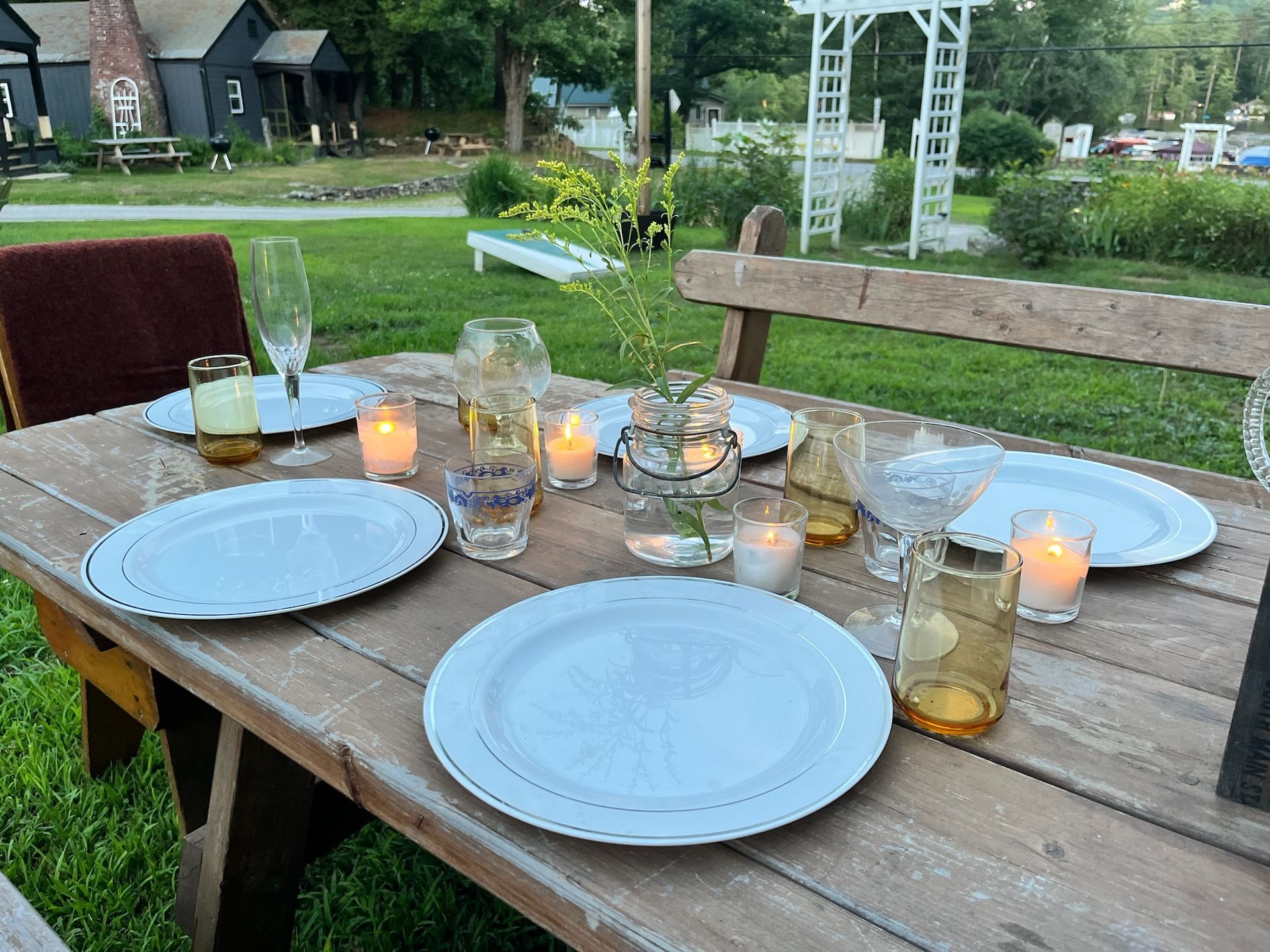 A wooden table with plates , glasses , and candles on it.