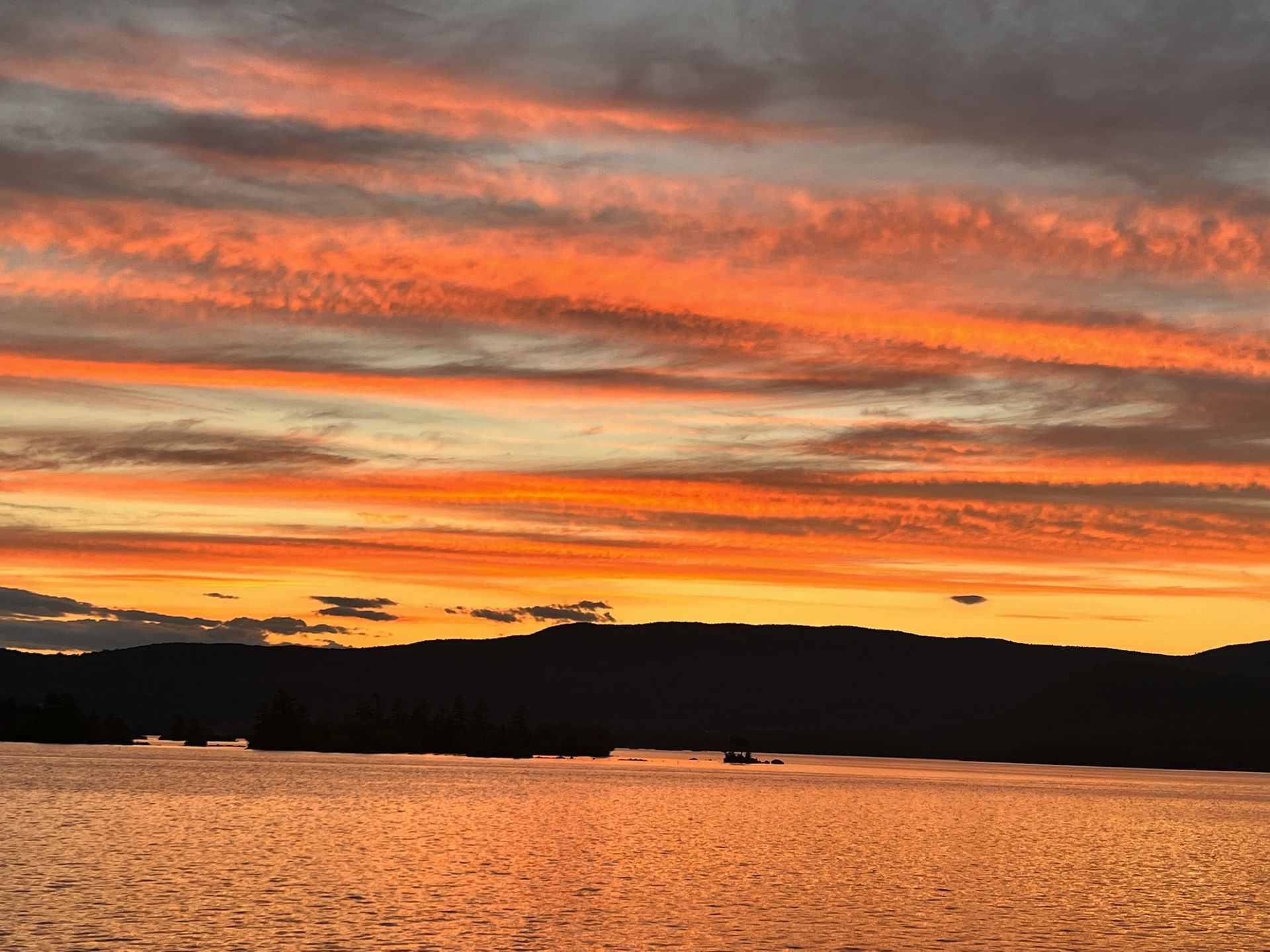 A sunset over a lake with mountains in the background