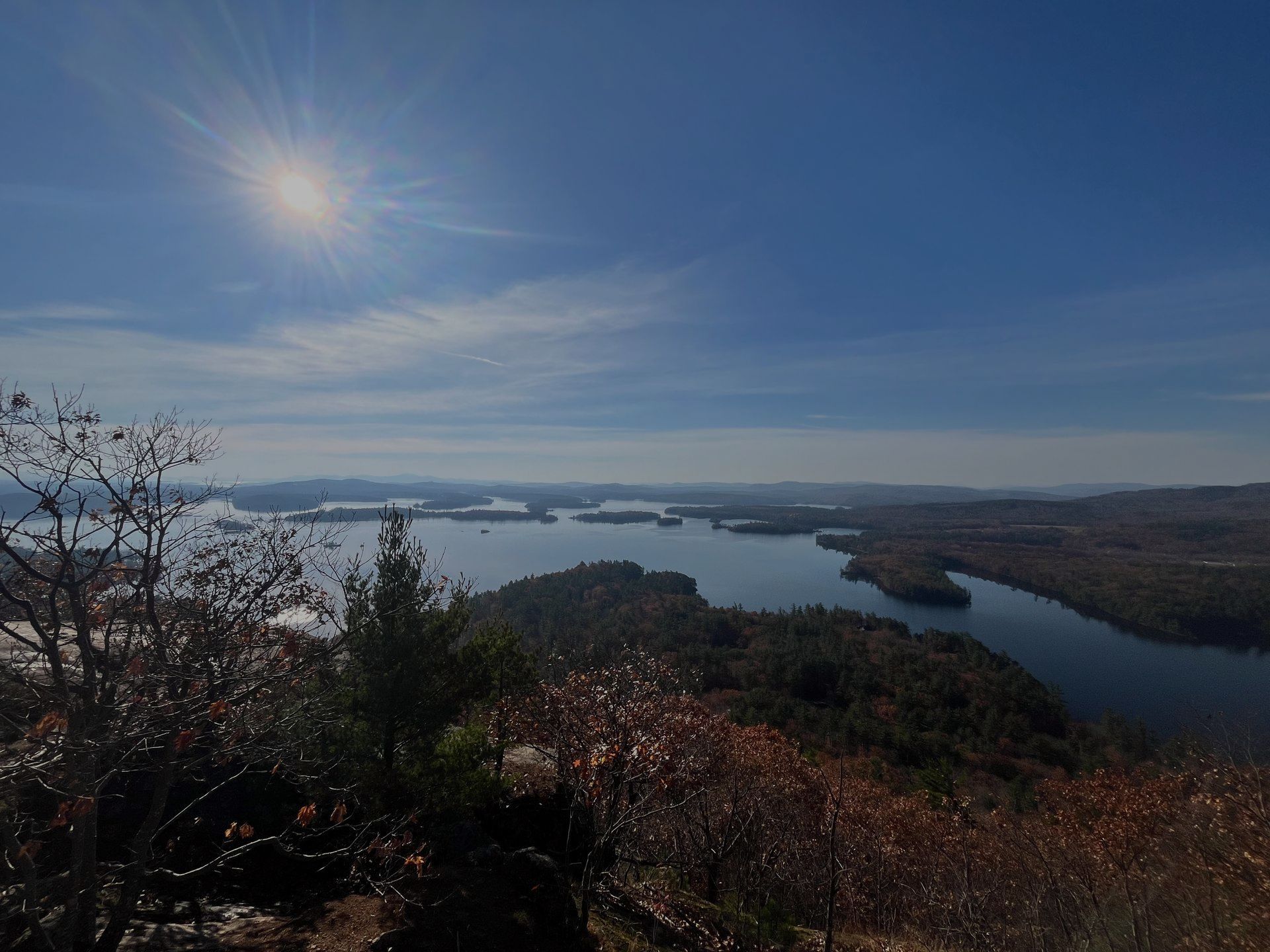 The sun is shining brightly over a lake surrounded by trees