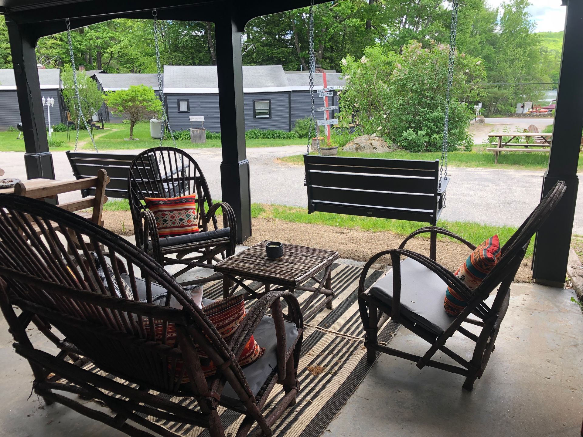 A porch with rocking chairs , a table and a swing.
