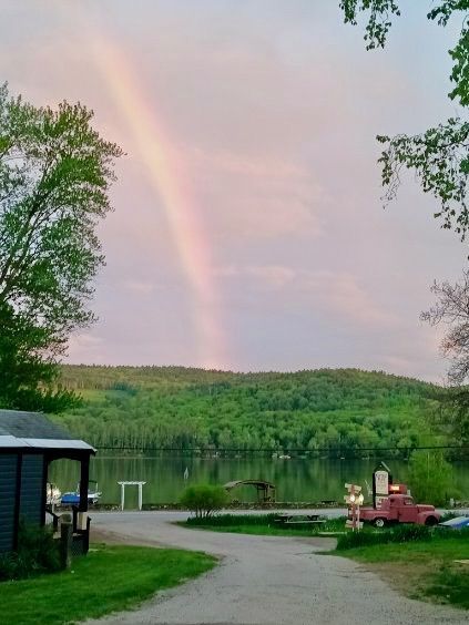 There is a rainbow in the sky over a lake.