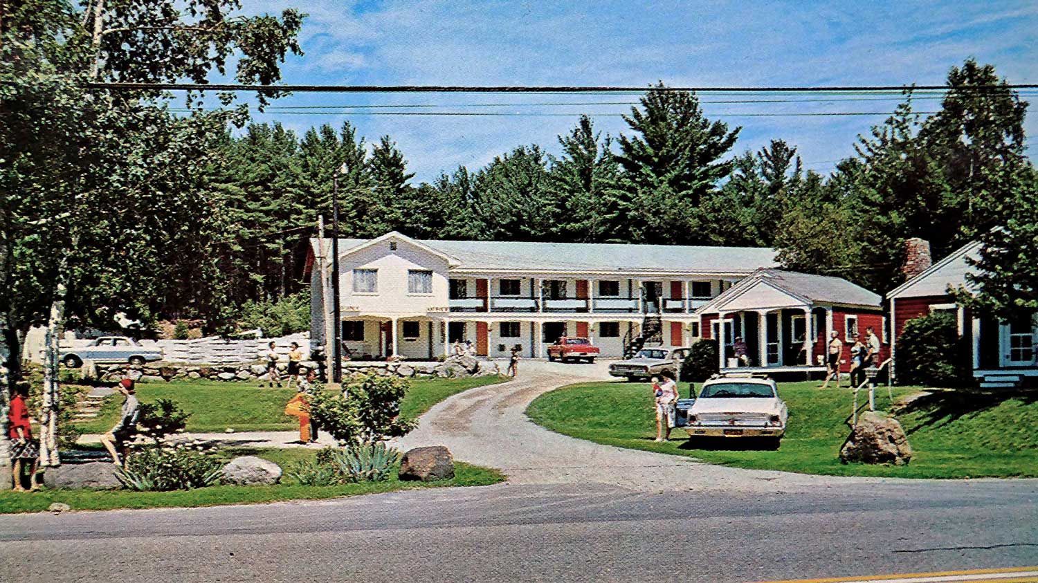 A motel with a lot of cars parked in front of it