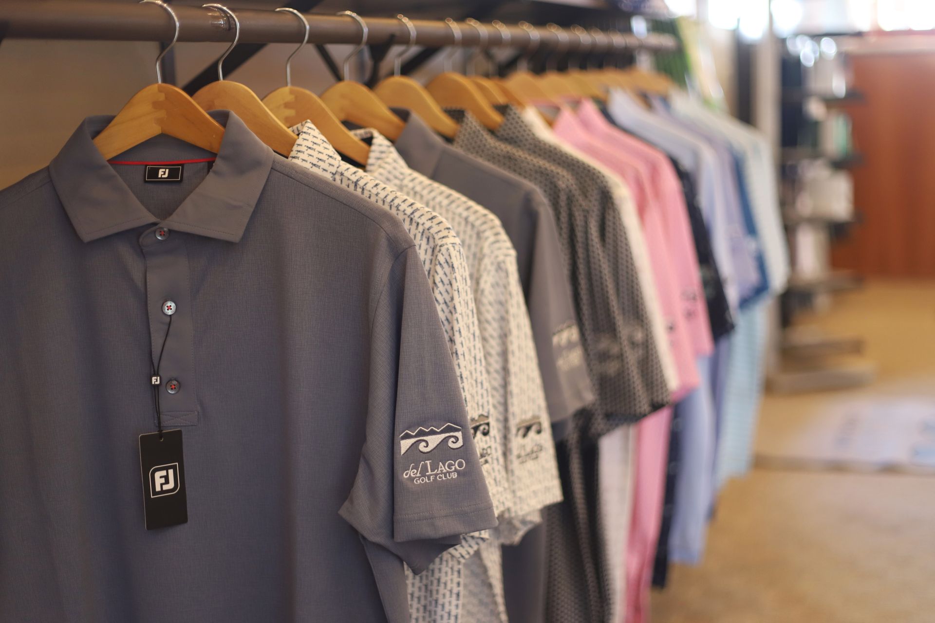 A golf apparel store with clothing racks displaying shirts, hats, and accessories.