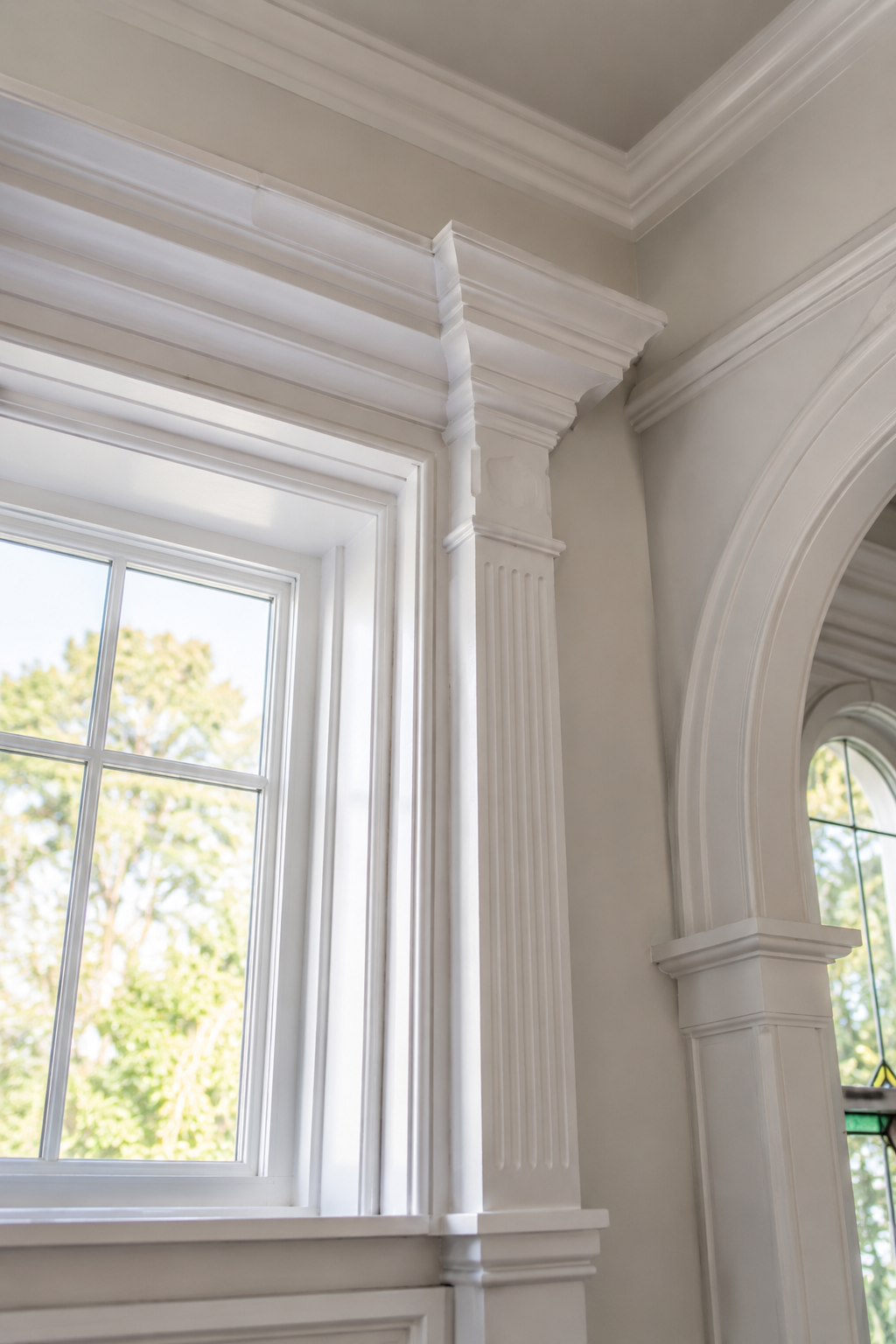 White-trimmed window and arched opening in a bright interior with crown molding